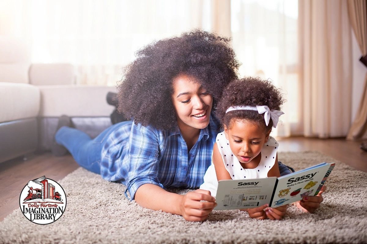 A mother and daughter reading an Imagination Library book together on the floor